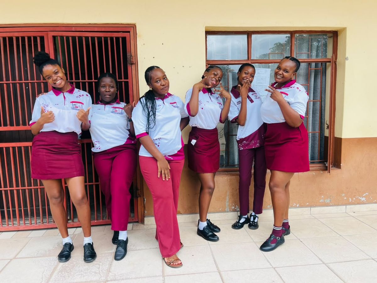 Learners in the Magigwana uniform golf shirt with maroon skirts and trousers outside a classroom